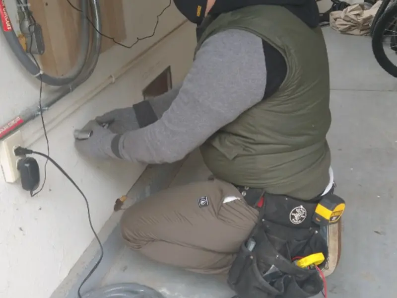 Electrician performing outlet wiring in a Adams garage
